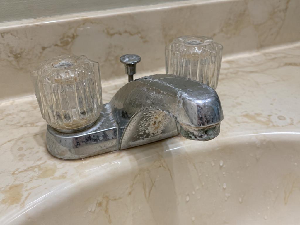 Before: Corroded faucet on a stained vanity top